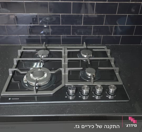 כיריים גז שחורים עם ארבעה מבערים במטבח מודרני